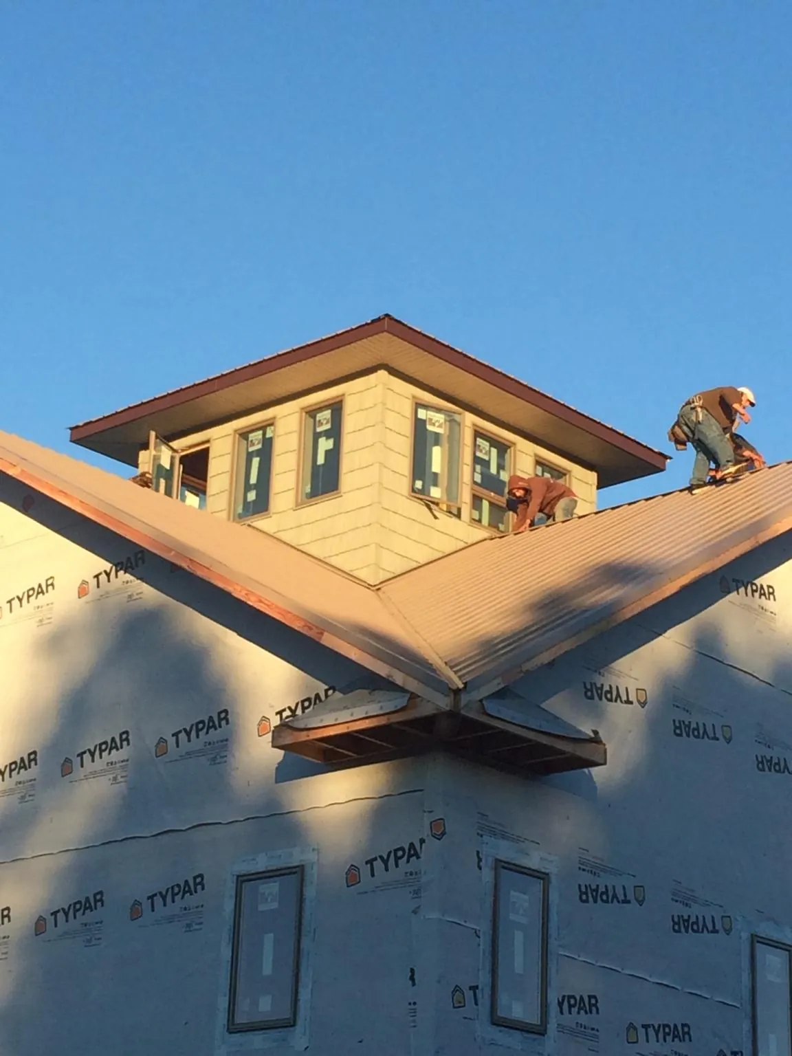 Roofers working around a rooftop cupola on a new metal roof at sunset — Roof Waterproofing in Darlington by Roofing Brothers